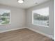 Bright bedroom with two windows, wood-look flooring, and neutral walls at 304 Cabarrus W Ave, Concord, NC 28025