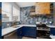 Close-up of kitchen featuring stainless steel appliances, marble backsplash, and blue lower cabinets at 304 Cabarrus W Ave, Concord, NC 28025