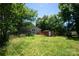 View of the overgrown backyard with storage shed and wooded fence line at 315 E Washington Ave, Bessemer City, NC 28016