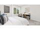 Bright bedroom featuring a large window with nature views, modern artwork, and a cozy reading nook with chair and desk at 3734 Coleman Dr, Charlotte, NC 28215
