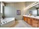 Bathroom featuring a soaking tub, wood cabinets, and wallpapered walls at 539 Turquoise Way, Fort Mill, SC 29708