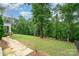 Large grassy backyard slopes gently, features a stone walkway and lush trees at 6873 Pine Moss Ln, Clover, SC 29710
