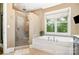 Luxurious bathroom featuring a glass-enclosed shower, soaking tub, and a large window at 6873 Pine Moss Ln, Clover, SC 29710