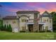 Home's rear exterior with stone chimney and balconies set against colorful sunset sky at 6873 Pine Moss Ln, Clover, SC 29710
