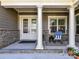 Cozy front porch with stone accents, white columns, and inviting decor with a chair, table, and potted plants at 705 Vintage Creek Dr, Matthews, NC 28104