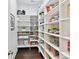 Organized pantry with shelving stocked with food items and storage containers with hardwood flooring at 705 Vintage Creek Dr, Matthews, NC 28104