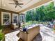 Inviting covered outdoor patio with wicker furniture, ceiling fan, and a serene view of the manicured backyard at 705 Vintage Creek Dr, Matthews, NC 28104