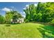 Expansive backyard with a well-manicured lawn, mature trees, a patio dining set, and a charming playhouse at 7930 Kelburn Ln, Charlotte, NC 28273
