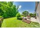 Lush backyard with a patio, outdoor dining set, fire pit, garden, and a mature tree, perfect for entertaining at 7930 Kelburn Ln, Charlotte, NC 28273