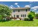 Spacious backyard featuring a lush lawn, patio with dining set and fire pit, plus mature trees and white flowering tree at 7930 Kelburn Ln, Charlotte, NC 28273