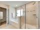 Bright bathroom with glass enclosed shower, soaking tub, tiled flooring, and white walls at 7930 Kelburn Ln, Charlotte, NC 28273
