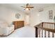 Cozy bedroom featuring plush armchair, wooden dresser and crib with stylish mountain themed decor and ceiling fan at 7930 Kelburn Ln, Charlotte, NC 28273