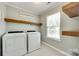 Bright laundry room featuring Whirlpool washer and dryer, floating shelves, and a Laundry Co. sign at 7930 Kelburn Ln, Charlotte, NC 28273
