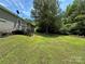 Home exterior with siding, stone foundation, wooden steps, green grass and wooded area at 9044 Forington Ln, Gastonia, NC 28056