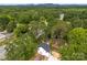 Aerial view of the home showing a dense tree line, a view of the mountains, and the surrounding community at 105 Spring Garden Dr, Gastonia, NC 28052
