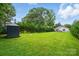 Large backyard with a storage shed, bordered by lush lawn, mature trees, and the house at 204 Craig St, Mount Holly, NC 28120