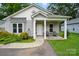 Charming single-story home with covered porch and cozy seating, complemented by a well-maintained front yard at 204 Craig St, Mount Holly, NC 28120