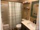 Compact bathroom showcasing a tub with curtain, a green vanity, toilet, and functional shelving at 2310 Gill Jordan Rd, Chester, SC 29706