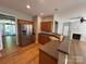 Open kitchen with stainless steel refrigerator, wood cabinets, and breakfast bar overlooking living room at 2567 Holly Oak Ln, Gastonia, NC 28056