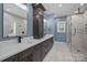 Primary bathroom with double vanity, standing storage cabinet, and stone tiled shower at 2577 Bonnybrook Cir, Rock Hill, SC 29732