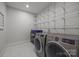 Laundry room with shelving, washer and dryer machines, and white tiling at 2577 Bonnybrook Cir, Rock Hill, SC 29732