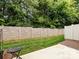 View of the backyard features a stone-look fence, grassy lawn, and small patio area at 403 Park Meadows Dr, Matthews, NC 28104