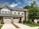 Beautiful townhome showcasing stone details, a driveway, well-kept lawn, and lush tree at 403 Park Meadows Dr, Matthews, NC 28104
