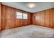 Spacious bedroom featuring wood paneling, neutral carpet, and a window for natural light at 409 Scaleybark Rd, Charlotte, NC 28209
