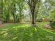 Expansive backyard featuring lush green grass, mature trees and landscaping, and a wooden fence for added privacy at 6116 Springhouse Ln, Charlotte, NC 28211