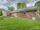 Spacious backyard with green grass, brick exterior, and mature shade trees at 6116 Springhouse Ln, Charlotte, NC 28211