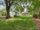 Beautiful backyard with green lawn, mature trees, and the rear view of a well-maintained brick home at 6116 Springhouse Ln, Charlotte, NC 28211