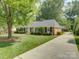 Side view of brick home with an expansive lawn, mature trees, and a long, paved driveway at 6116 Springhouse Ln, Charlotte, NC 28211