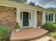 Inviting front porch featuring a dark-colored front door, decorative plants, and traditional brickwork at 6116 Springhouse Ln, Charlotte, NC 28211