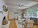 Bright living room featuring a white brick fireplace, hardwood floors, ceiling fan, and a comfortable seating area at 6116 Springhouse Ln, Charlotte, NC 28211