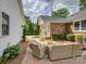 Relaxing patio with wicker furniture, brick pavers, lush landscaping, and shade at 6116 Springhouse Ln, Charlotte, NC 28211