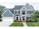 Charming two-story home showcasing a well-maintained lawn, black window shutters, and a two-car garage at 6400 Morningsong Ln, Charlotte, NC 28269