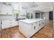 Bright kitchen features white cabinets, a spacious island with a marble countertop, stainless steel appliances, and hardwood floors at 6400 Morningsong Ln, Charlotte, NC 28269