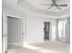 Bright main bedroom featuring a tray ceiling, ceiling fan, and ensuite bathroom entrance at 6400 Morningsong Ln, Charlotte, NC 28269