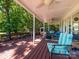 Inviting covered deck features a seating area with plush chairs, ceiling fans, and a beautiful view of the lush backyard at 7356 Terrace Dr, Charlotte, NC 28211