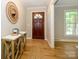 Inviting home foyer featuring hardwood floors, a decorative mirror, and a wooden entry door at 7356 Terrace Dr, Charlotte, NC 28211