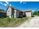 Exterior view of a tan home with an overgrown yard and a gravel driveway at 921 W 1St St, Lowell, NC 28098