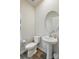 Stylish half bathroom features a pedestal sink, round mirror, and wood-look flooring at 1015 Maltby St, Charlotte, NC 28217