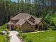 An aerial view of an estate home showcasing a lush landscape, circular driveway, and attached garages at 102 Antioch Plantation Dr # 18, Matthews, NC 28104