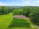 Aerial view of a brick home with a large, green lawn, surrounded by lush trees, offering a serene setting at 1081 Long Dr, Newton, NC 28658
