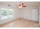 Sunny bedroom with light wood flooring, large windows, ceiling fan, and a door leading to a closet at 10945 Winterbourne Ct, Charlotte, NC 28277