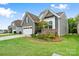 A charming exterior view showing a manicured lawn and stylish siding with stone accents on a sunny day at 12637 Belmont Mansion Dr, Charlotte, NC 28273