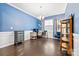 Bright office with blue accent wall, white trim, hardwood floors, and elegant chandelier lighting at 12637 Belmont Mansion Dr, Charlotte, NC 28273
