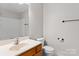 Bathroom with wood vanity, white sink and toilet, and shower with a white surround at 128 Locomotive Ln, Mooresville, NC 28115