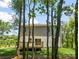 A two-story home with a wooden deck in a green backyard viewed through trees under a blue sky at 2313 Stallings Rd, Harrisburg, NC 28075