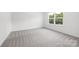 A sunlit bedroom featuring neutral carpet, white walls, and a window at 2313 Stallings Rd, Harrisburg, NC 28075